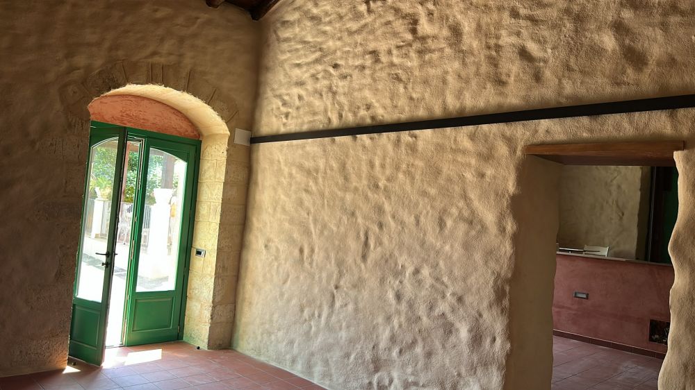 Ingresso interno con portone in legno verde incorniciato da un arco originale in pietra calcarea