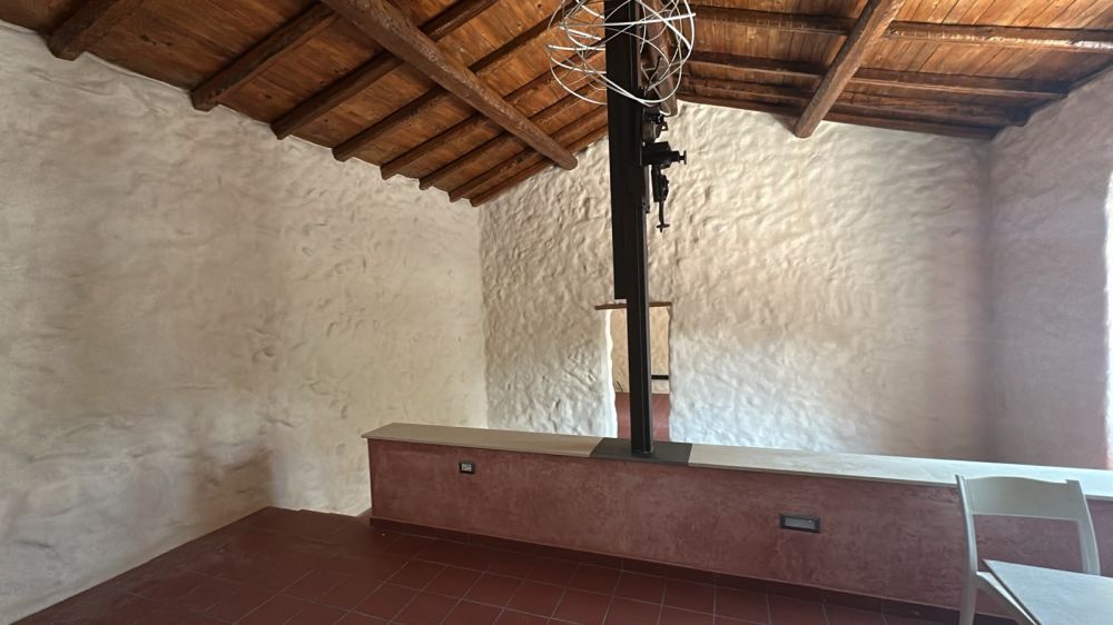 Vista dal livello rialzato interno della pressa agricola d'epoca e delle pareti in pietra.