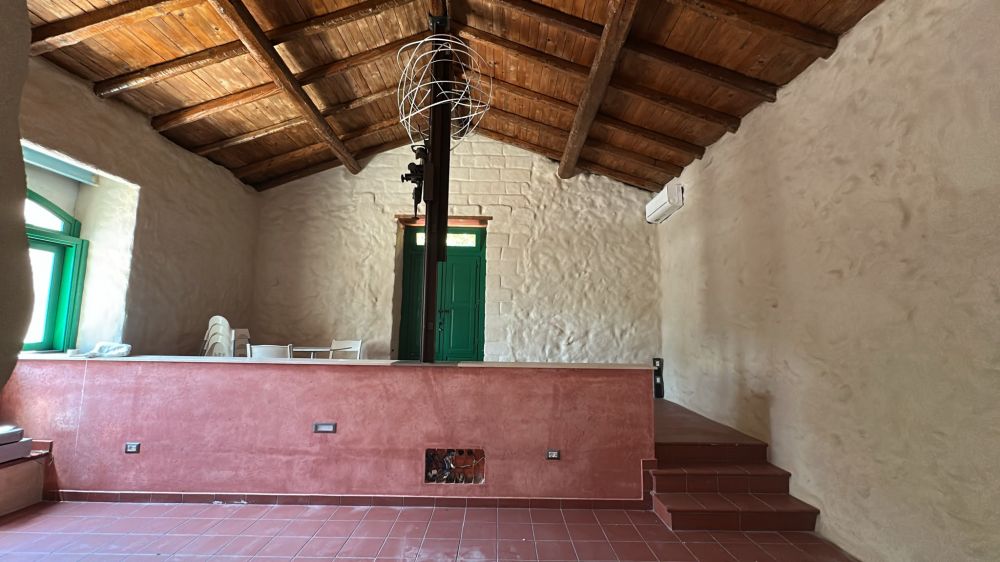Sala centrale con antica pressa agricola restaurata, soffitto in legno e bancone divisorio