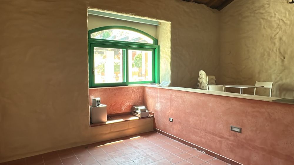 Angolo accoglienza interno con grande finestra ad arco in legno e panca integrata